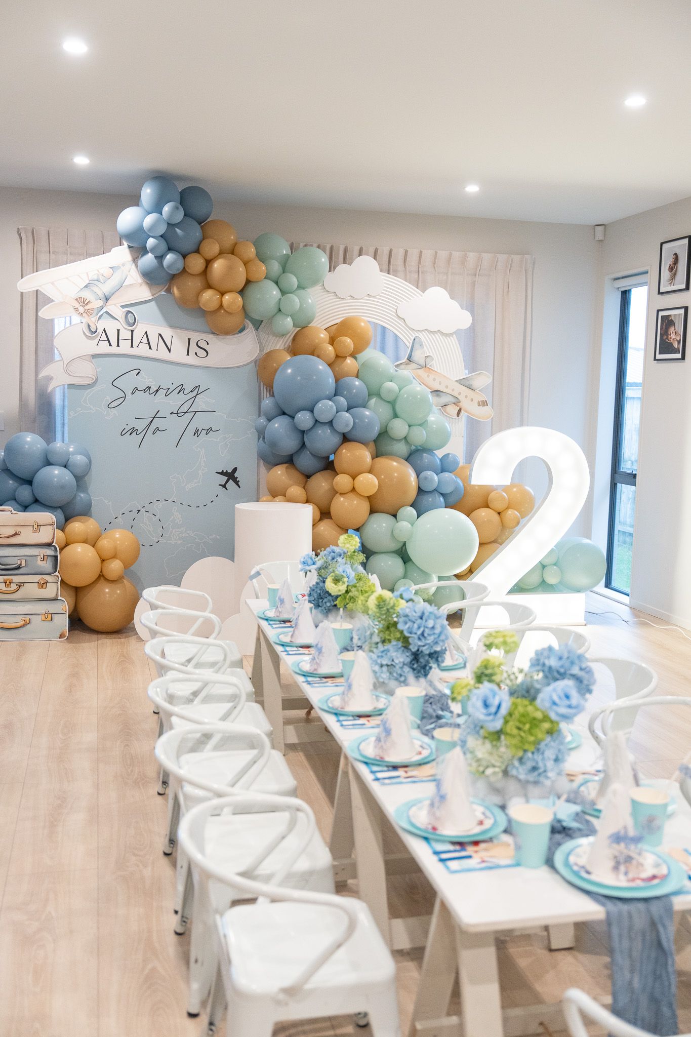 Ahan’s 2nd birthday party setup at home in Auckland with travel-themed balloons, kids table, floral centrepieces and glowing number two display