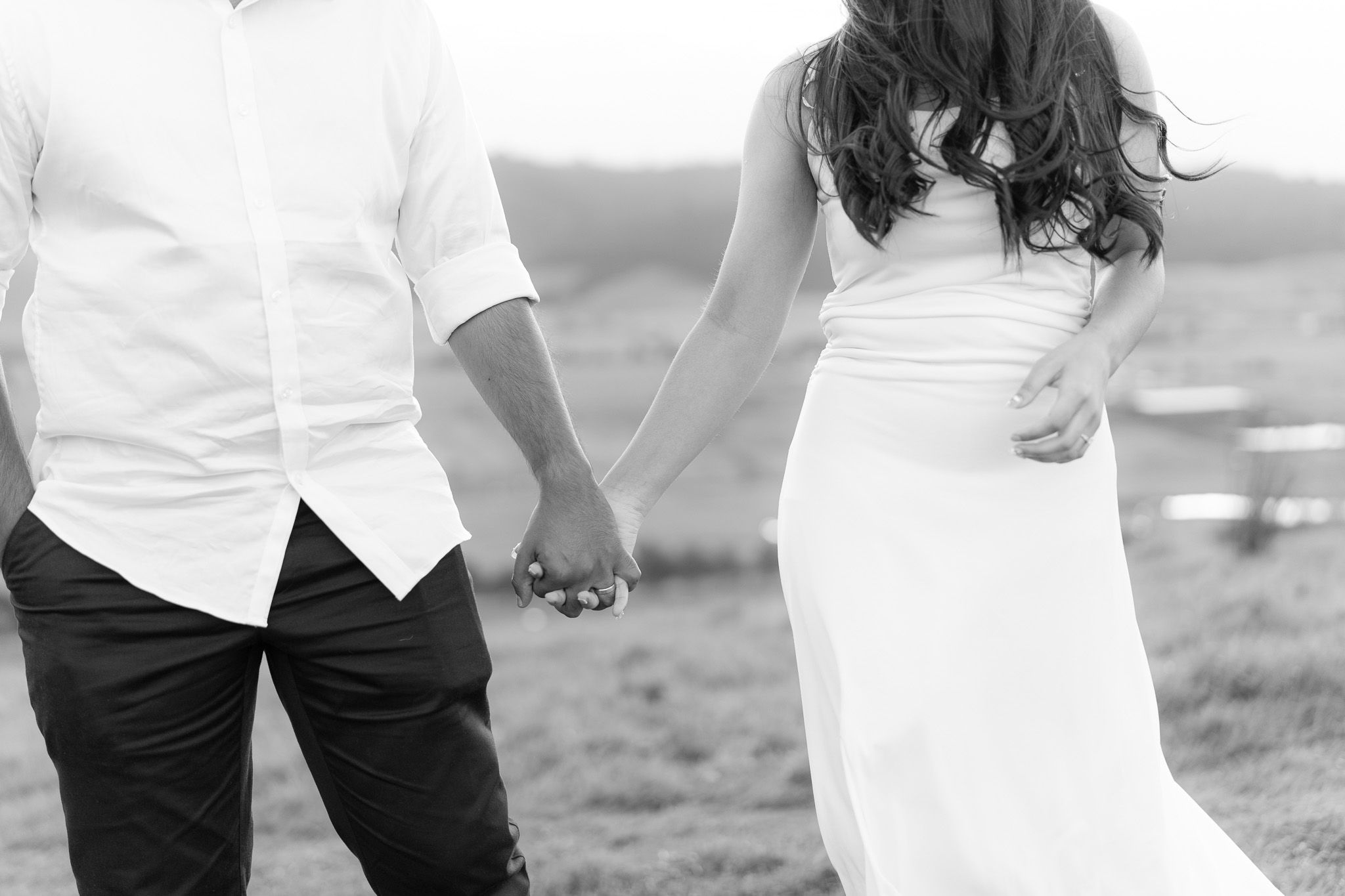 Close up black and white couples photography of hands holding with engagement ring detail during romantic sunset shoot in Auckland