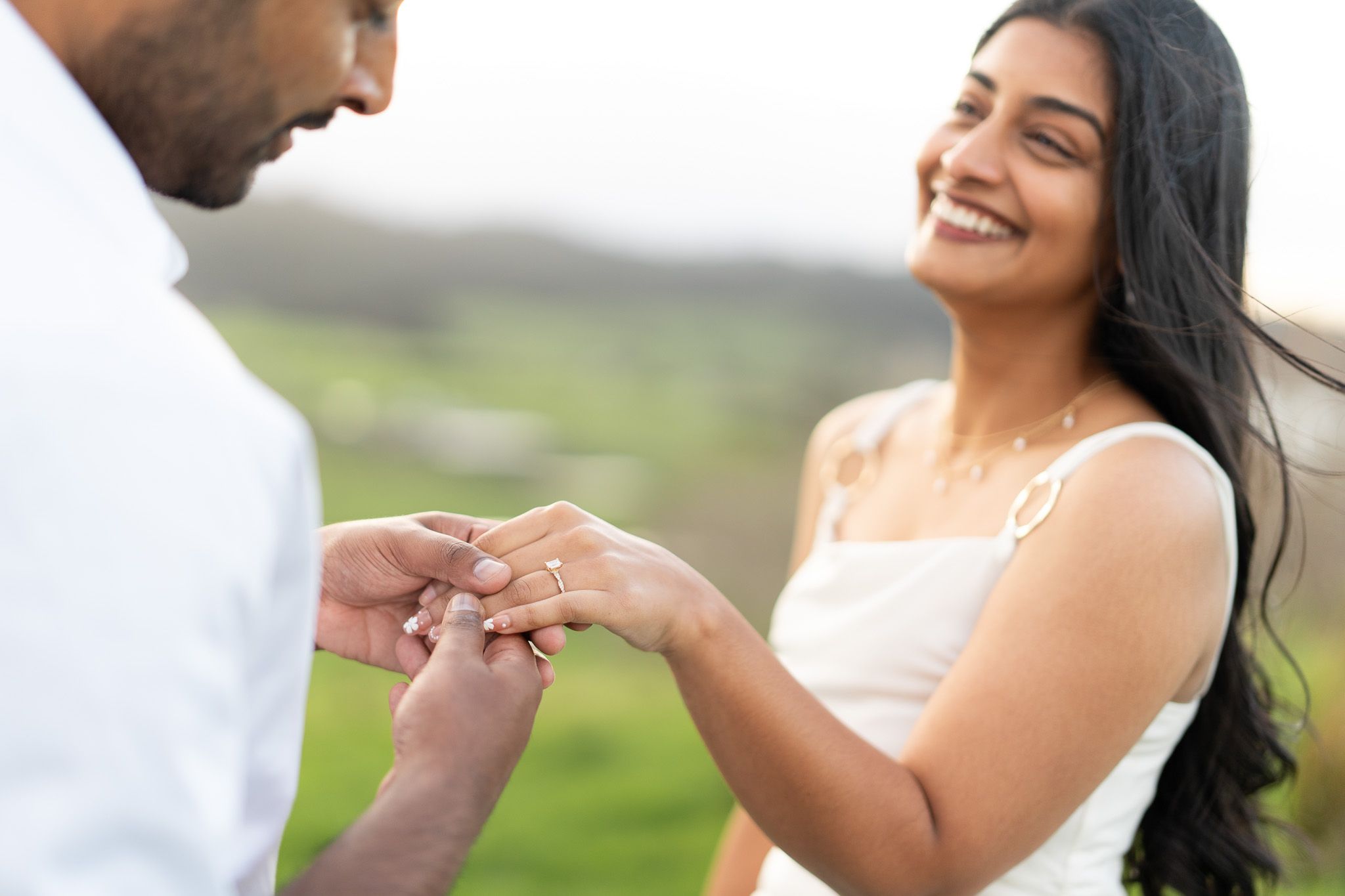 Close up engagement photography moment with ring placement and smiling couple during intimate sunset couples photography in Auckland