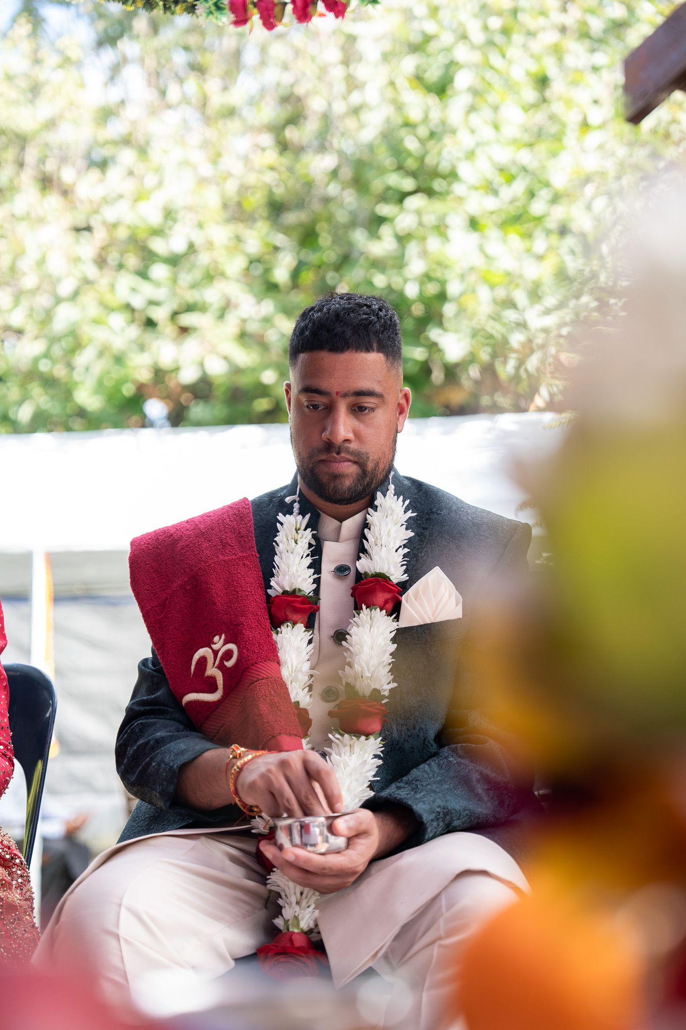 Groom seated during Hindu pre wedding Shantak ceremony with traditional attire and garlands captured in Indian wedding photography Auckland