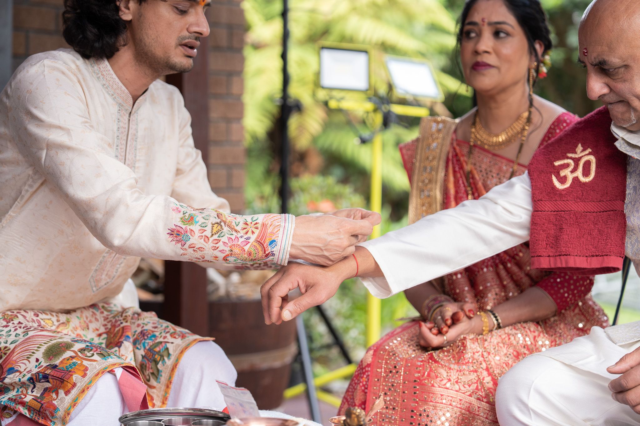 Hindu priest tying a sacred thread during Milan’s Shantak ceremony with family seated nearby
