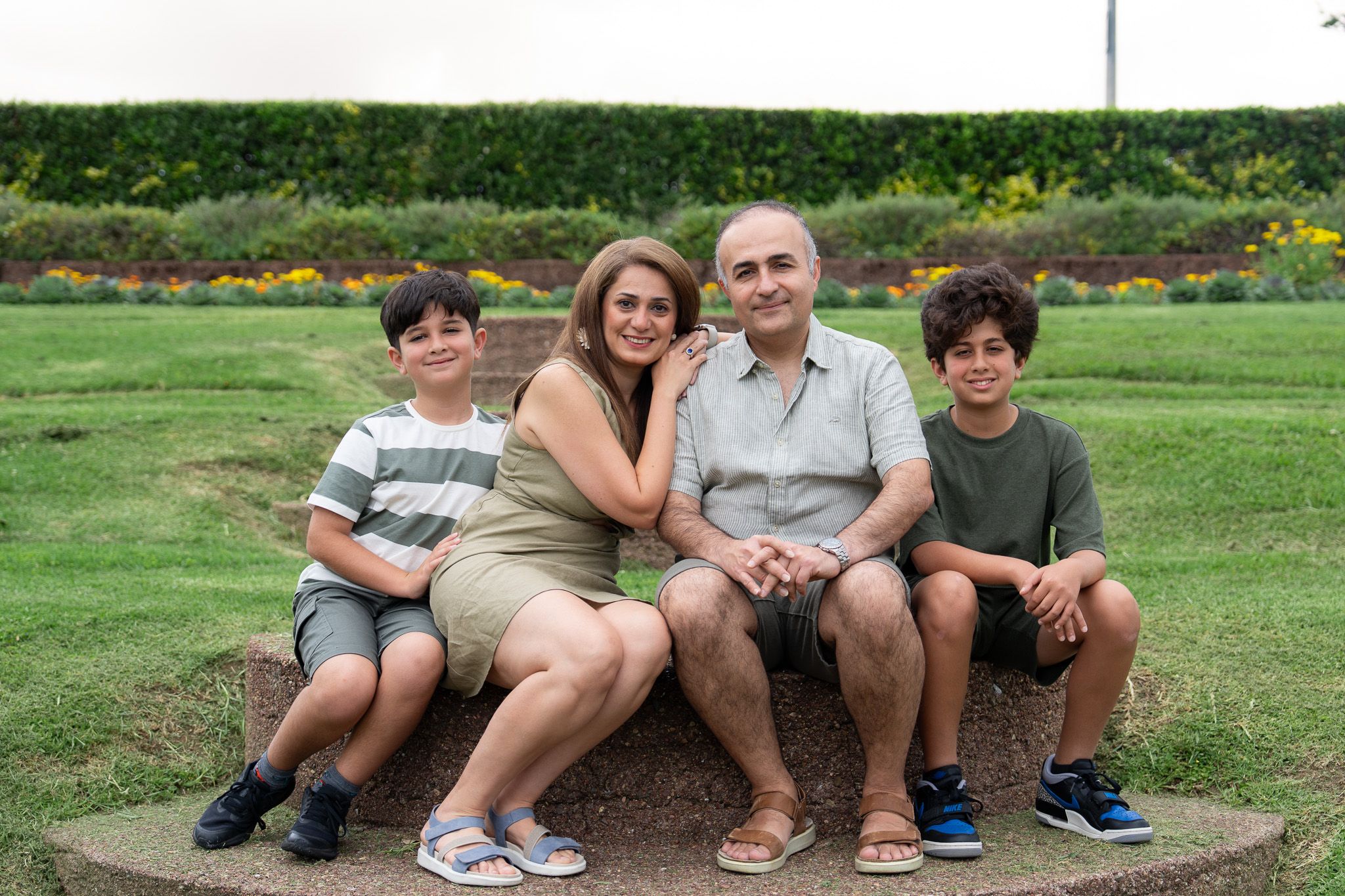 Relaxed family photography in Auckland with Mona, Ali and their two boys sitting together in a garden at Michael Joseph Savage Memorial