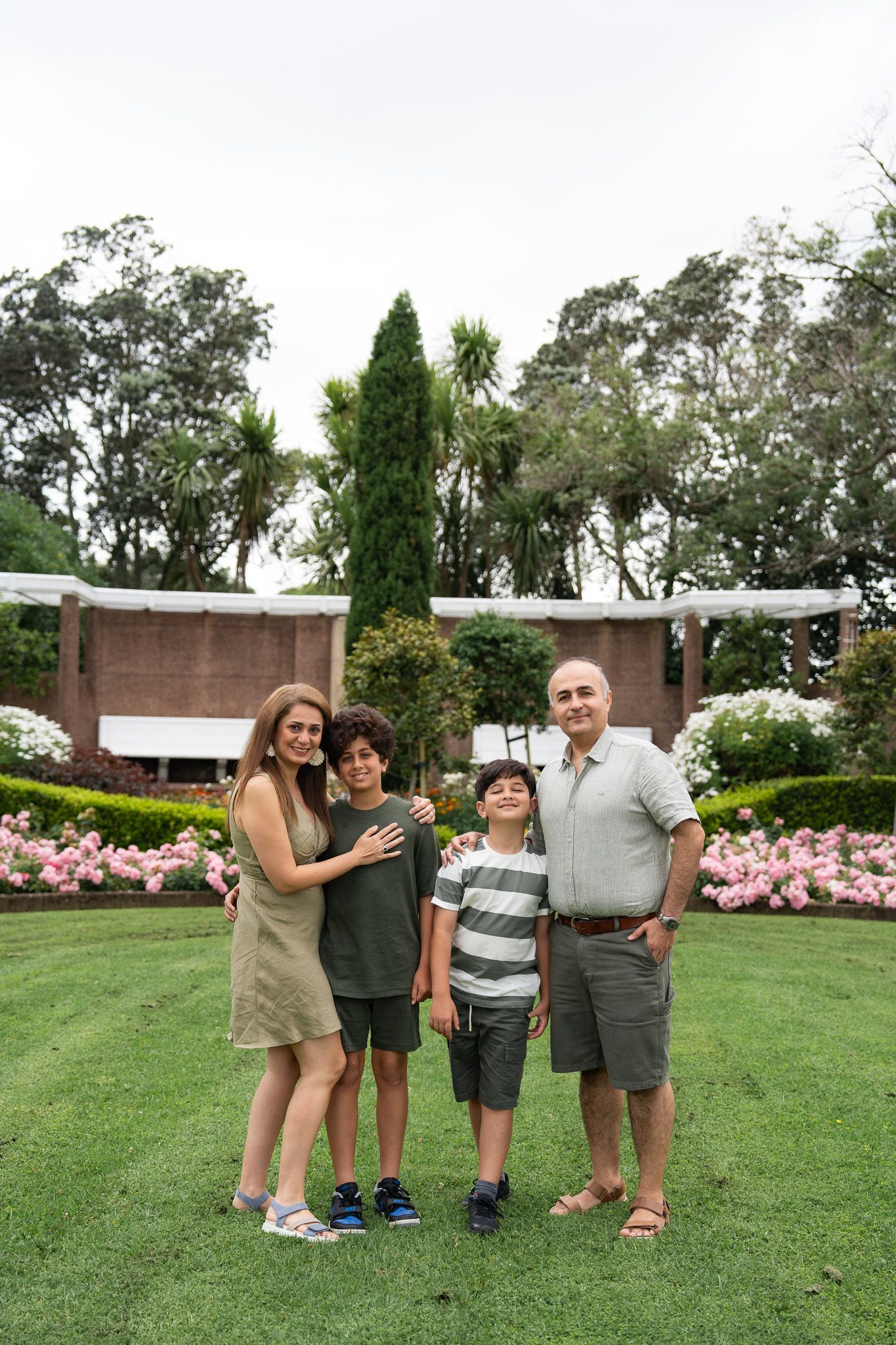 Mona, Ali and their two boys standing together in the gardens at Michael Joseph Savage Memorial during a family photoshoot in Auckland
