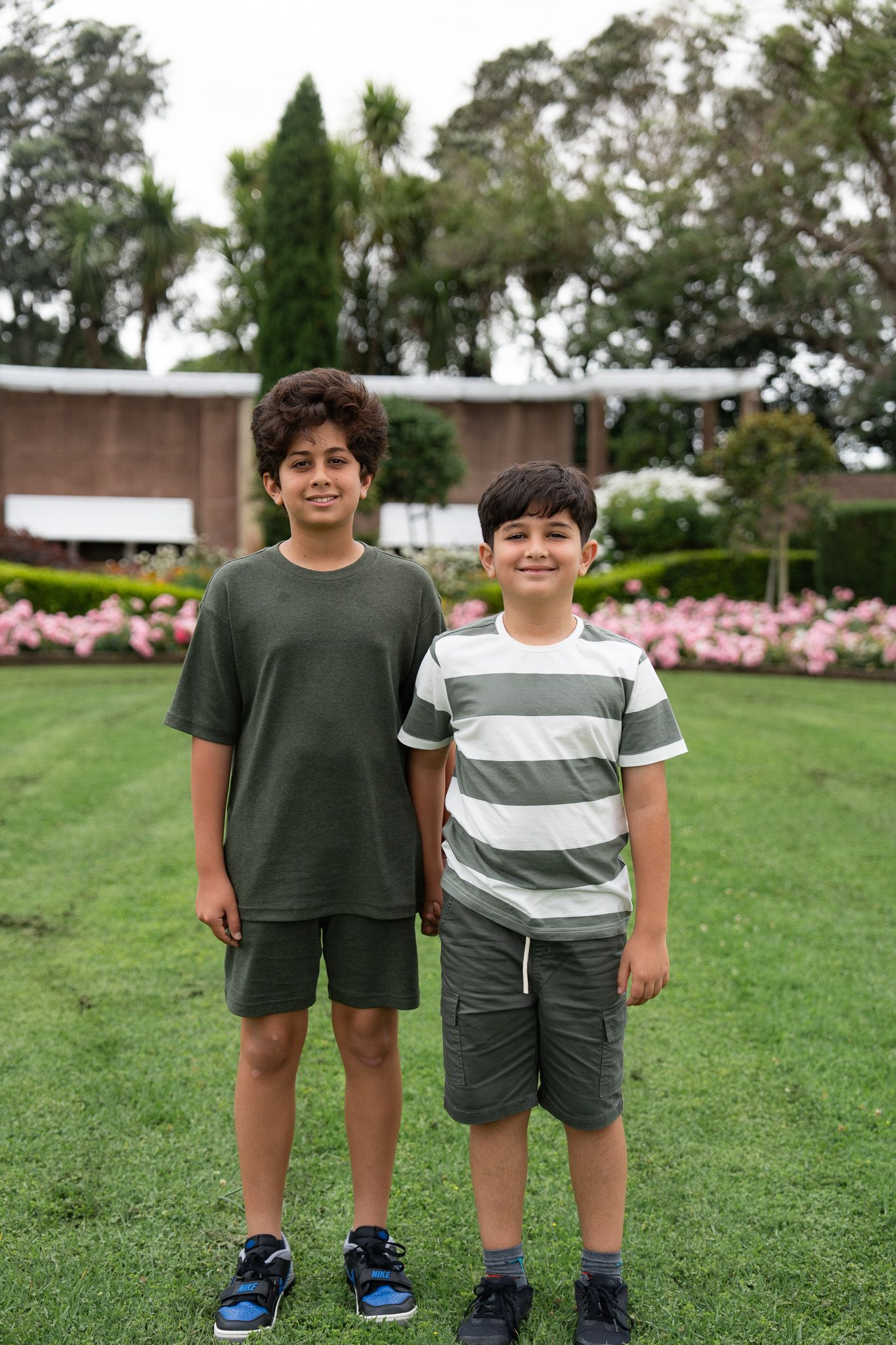 Two brothers smiling together in the gardens at Michael Joseph Savage Memorial during a relaxed family photoshoot in Auckland