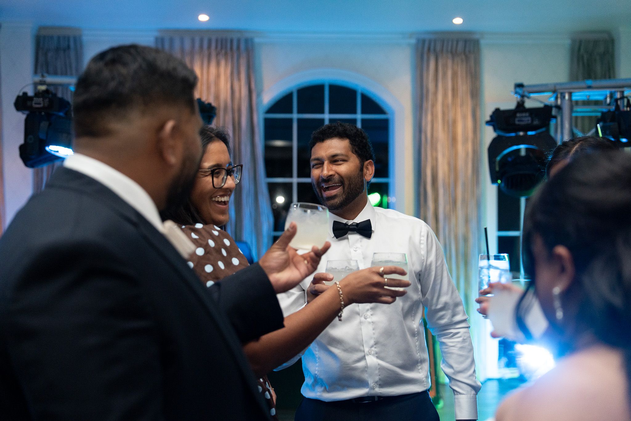 Guests laughing with drinks on dance floor at Indian wedding reception Bracu Estate South Auckland candid wedding photography