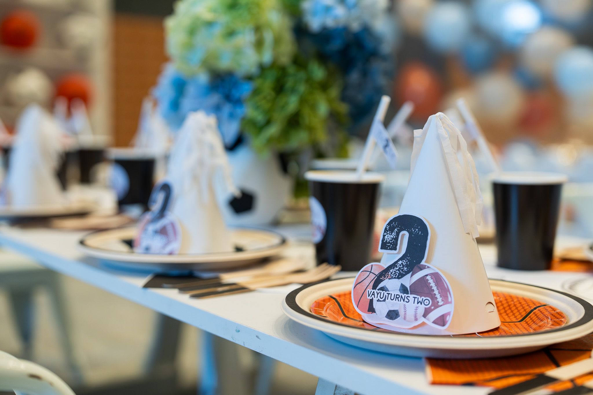 Sports themed birthday table setting with party hats, black cups and blue florals for a 2nd birthday photography session