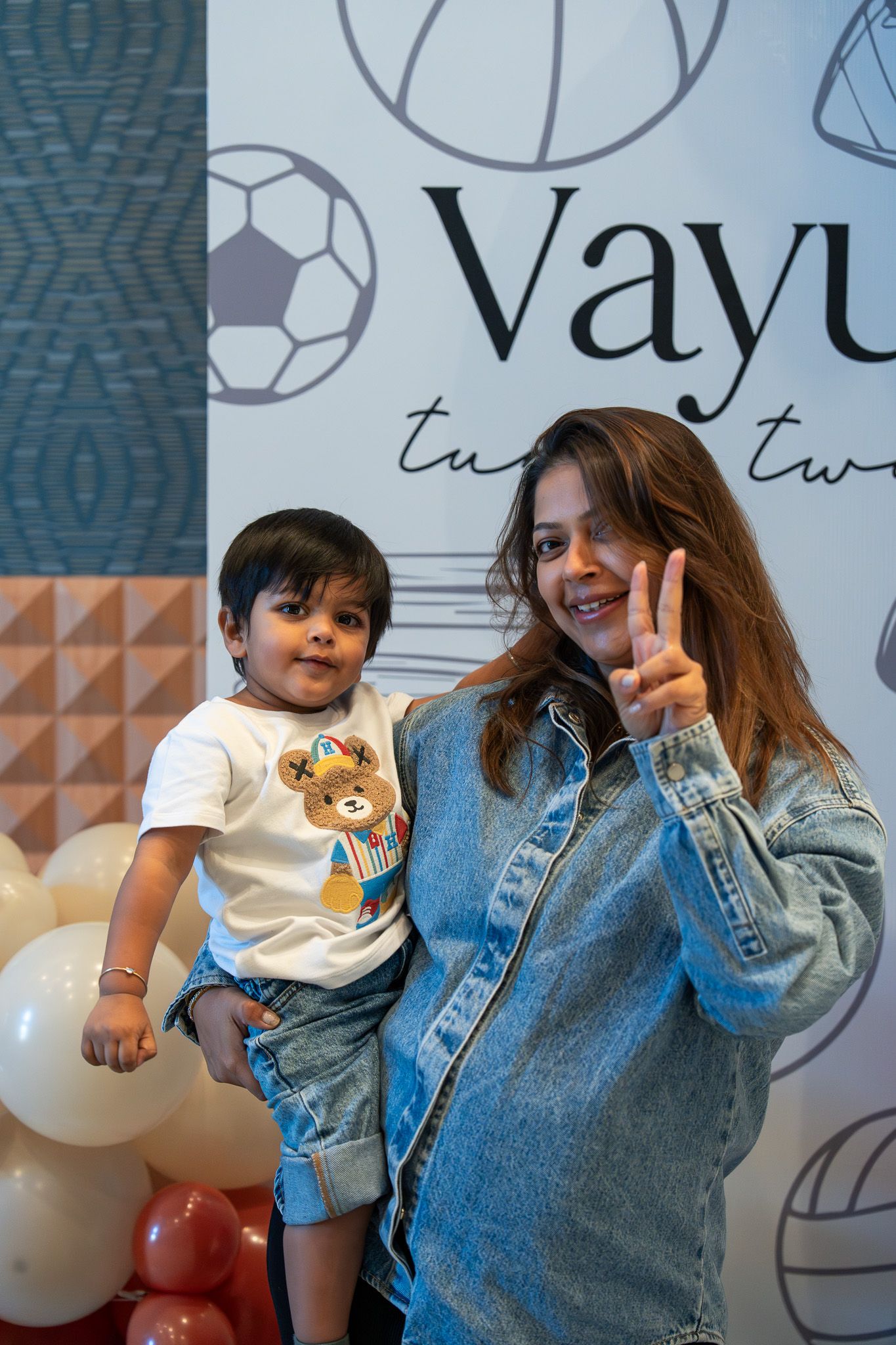 Mother and son smiling in front of birthday signage with balloons in the Razzle Dazzle Room at Naumi Auckland Airport Hotel in Auckland