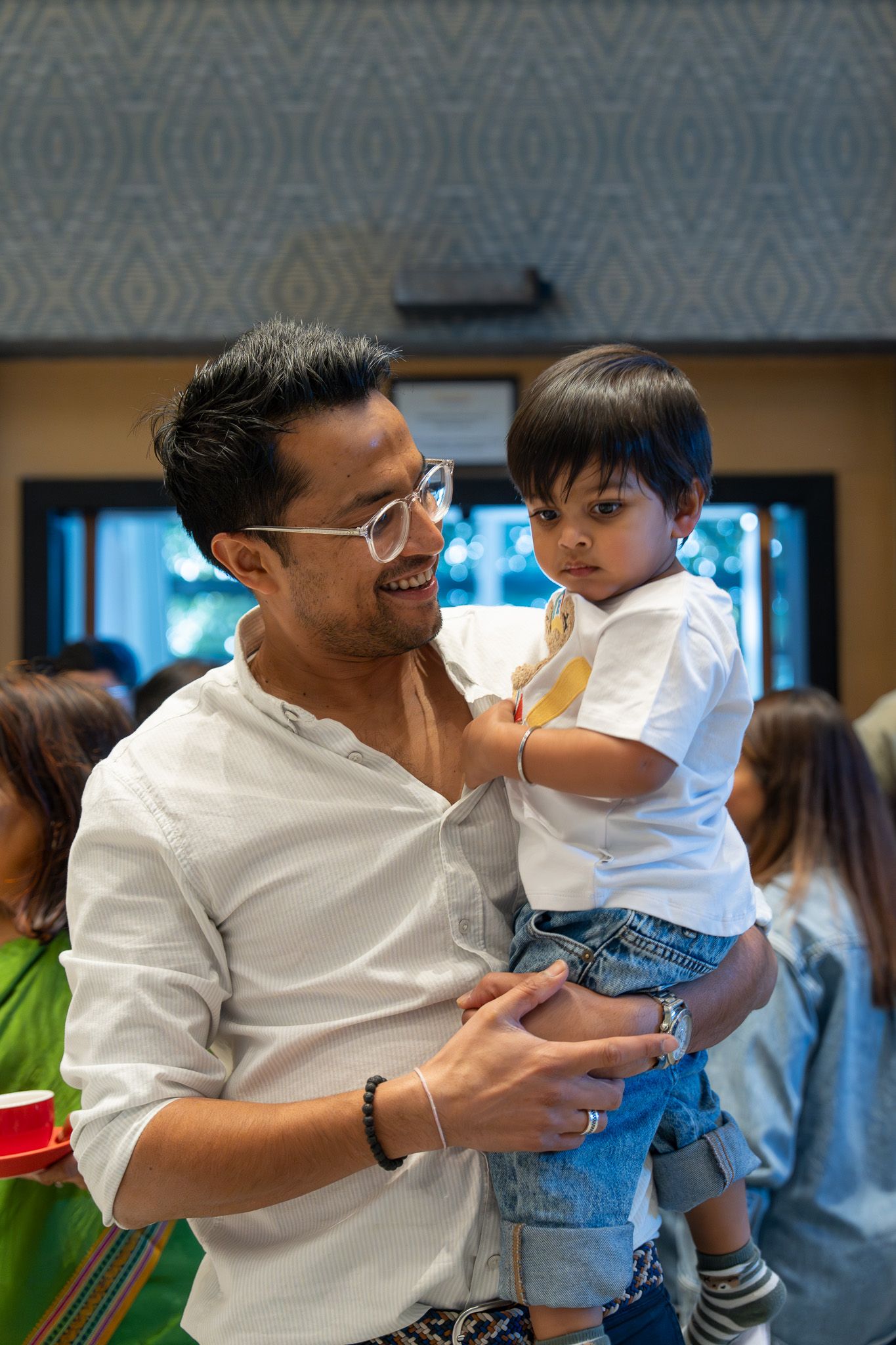 Uncle holding toddler while smiling at a fun-filled kids birthday celebration in Auckland
