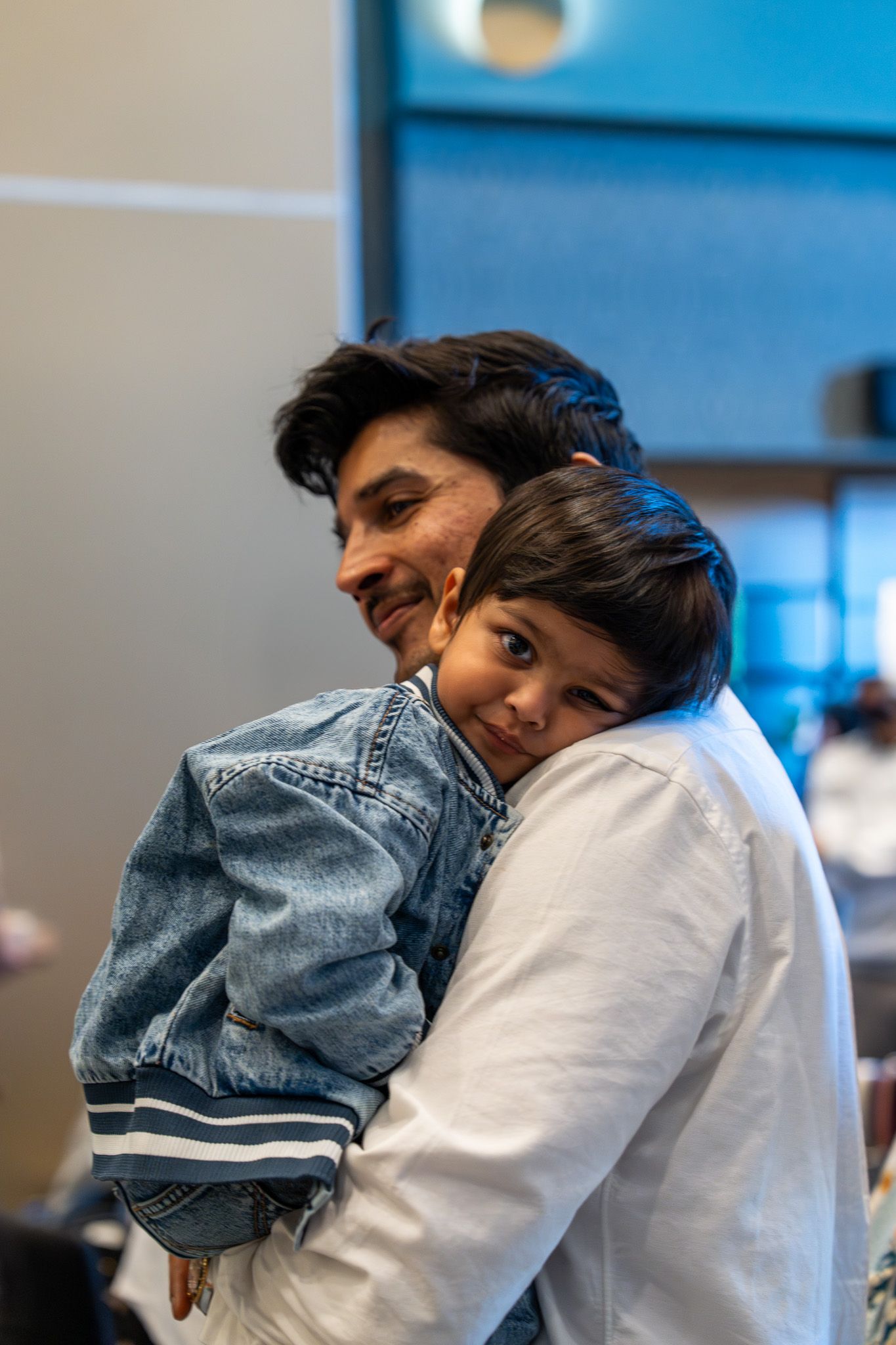 Young boy resting on his father’s shoulder during a sweet moment at a kids birthday party in Auckland