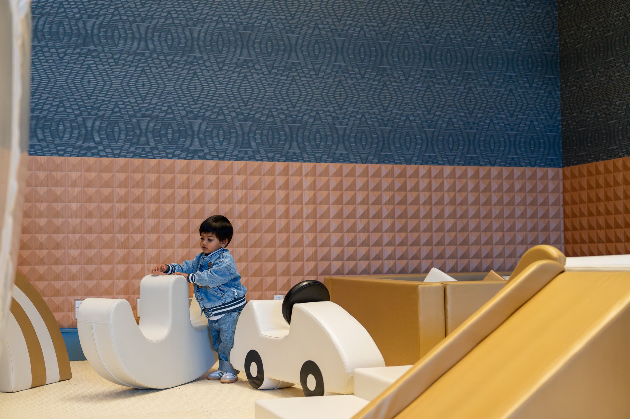 Young boy playing with ride-on toys in the Razzle Dazzle Room at Naumi Auckland Airport Hotel during a kids birthday party in Auckland