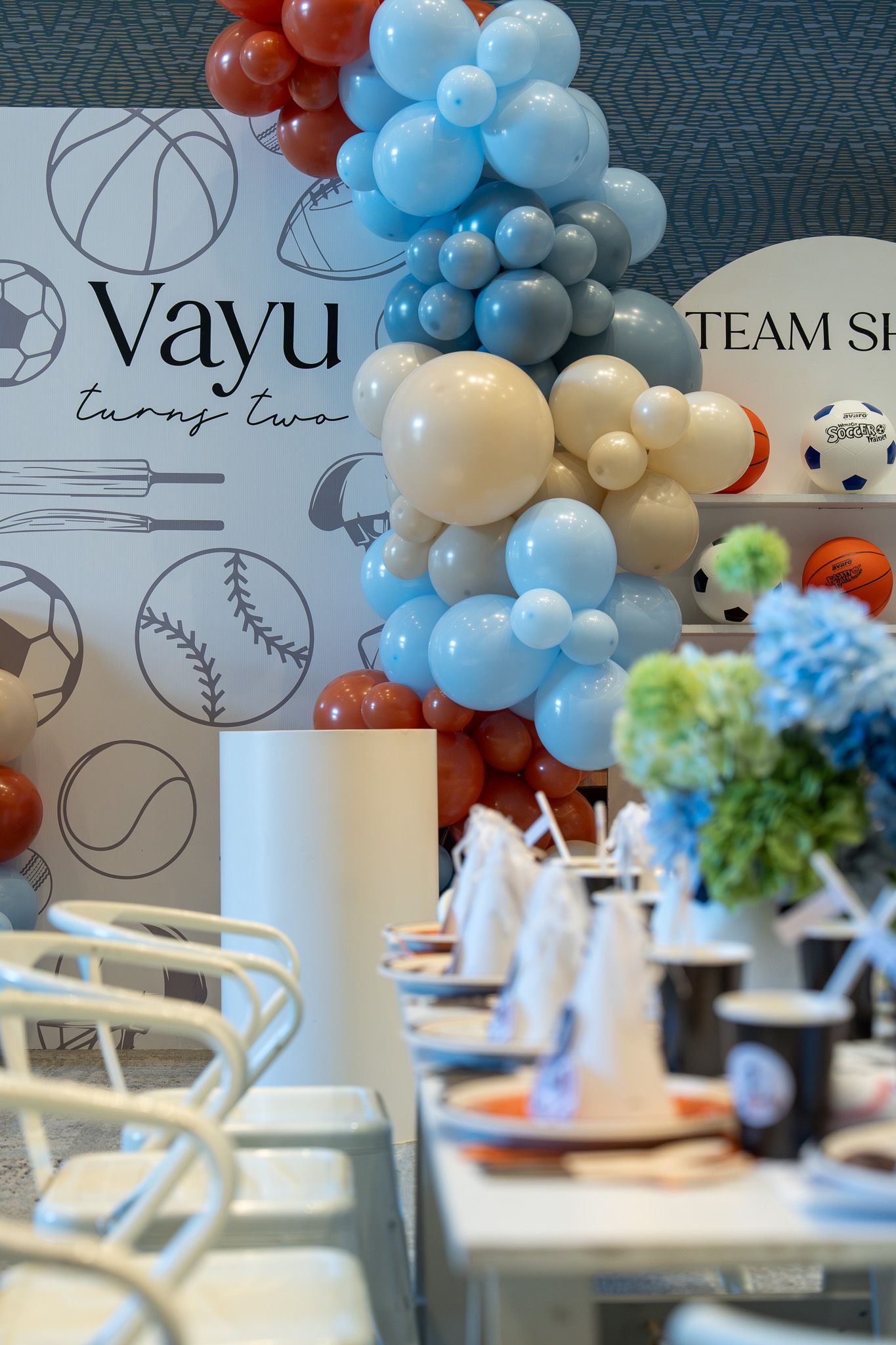 Balloon garland and sports-themed table setup at Vayu’s second birthday party in the Razzle Dazzle Room at Naumi Auckland Airport Hotel