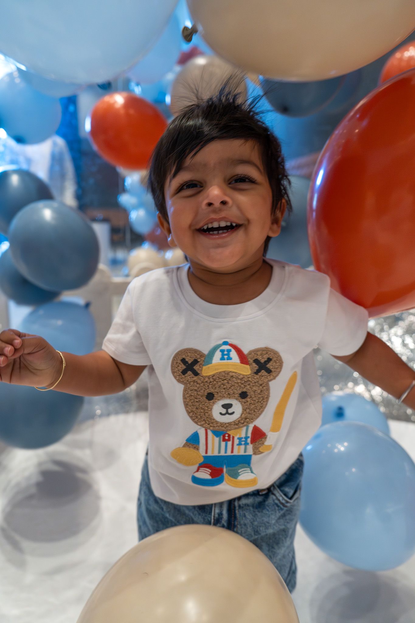 Laughing toddler surrounded by pastel balloons during a playful moment at a birthday party in Auckland